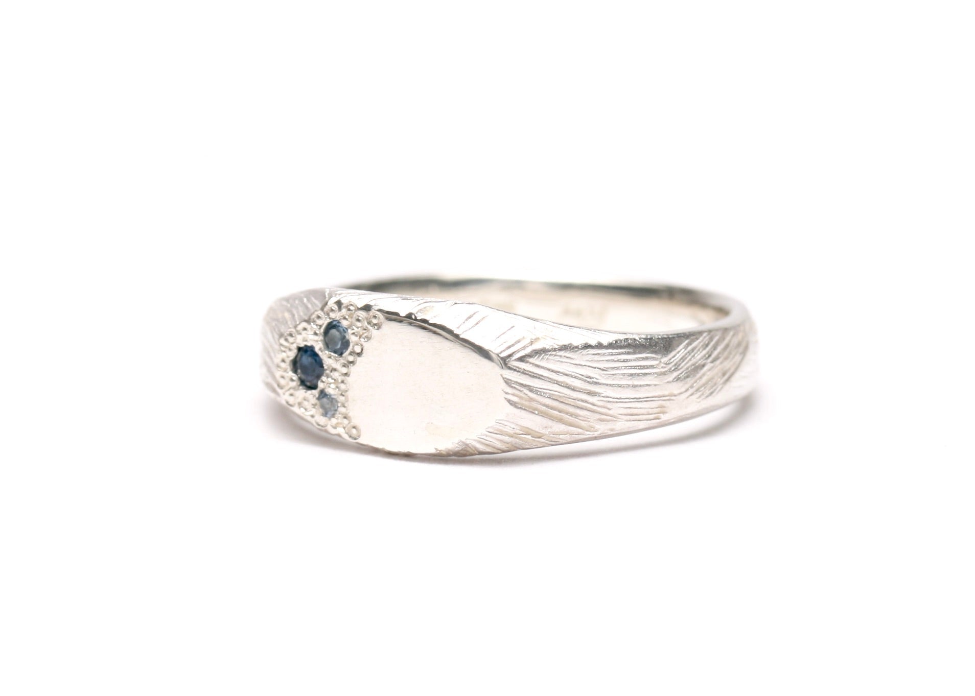 Silver ring with bark like texture design and embedded blue sapphires